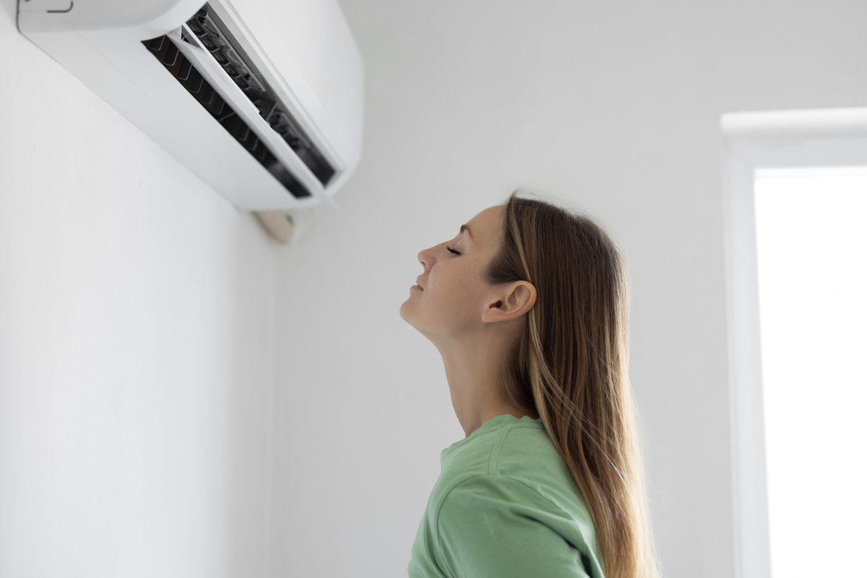 A woman enjoys cool, comfortable air from a wall-mounted AC unit in her coastal New Jersey home.